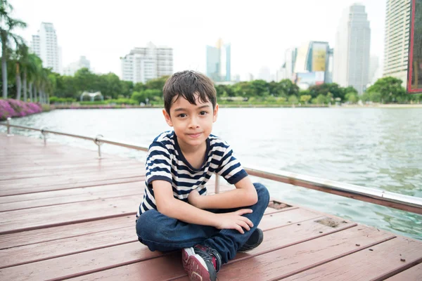 Petit garçon assis près du lac de la lagune dans la pard — Photo