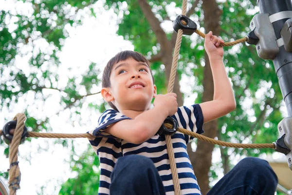 Kleine jongen klimmen touw op speelplaats — Stockfoto