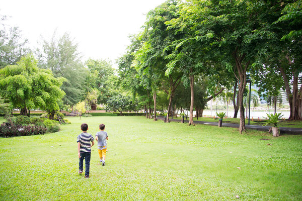 Little sibling boy running together in the park