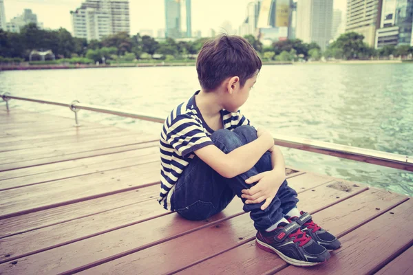 Little boy sitting nearby the lagoon lake  in the pard — Stock Photo, Image