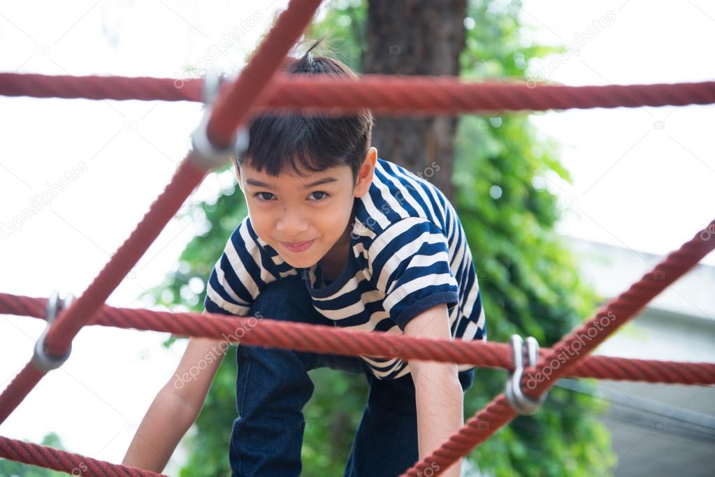 Little boy climbing rope at playground