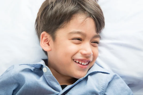 Pequeño niño acostado en la cama linda cara hermosa sobre fondo blanco —  Fotos de Stock