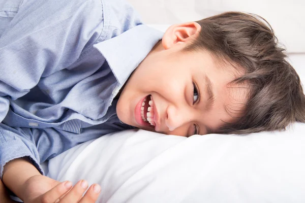 Маленький мальчик лежит на кровати милое красивое лицо на белом фоне — стоковое фото