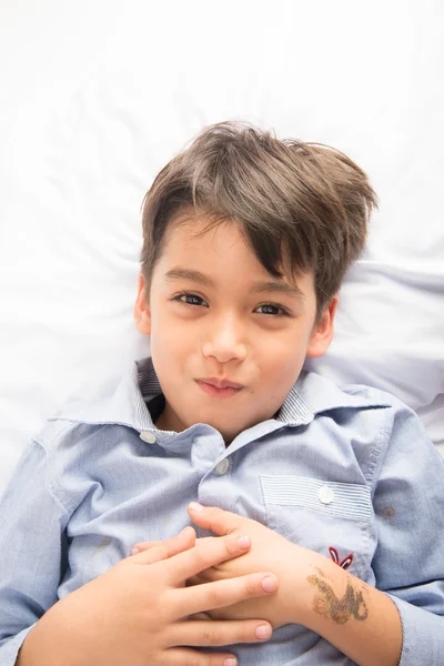 Pequeño niño acostado en la cama linda cara hermosa sobre fondo blanco —  Fotos de Stock