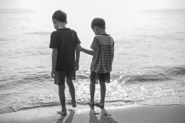 Plaj birlikte siyah ve beyaz üzerinde duran küçük kardeş çocuk