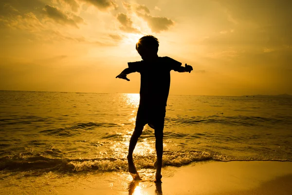 Silhueta de menino saltando sobre a onda de praia — Fotografia de Stock