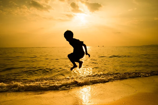 Silhueta de menino saltando sobre a onda de praia — Fotografia de Stock