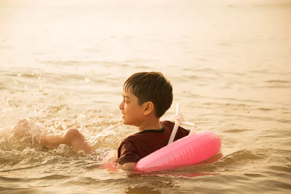 Kleine jongen zwemmen op het strand — Stockfoto