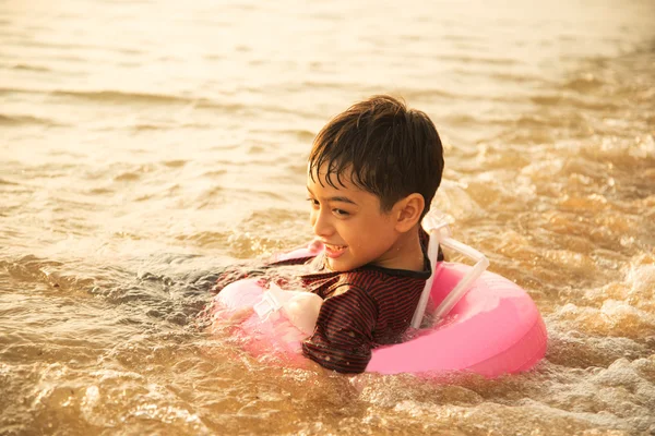 Kleine jongen zwemmen op het strand — Stockfoto