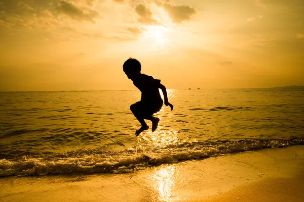 Silhouette of llittle boy jumping over the beach wave Royalty Free Stock Photos