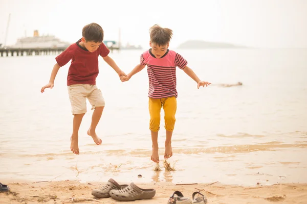Küçük kardeş çocuk plaj üzerinde atlama — Stok fotoğraf