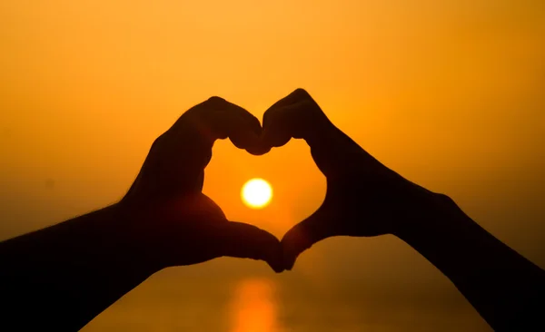 Hand making heart shape over sunset — Stock Photo, Image