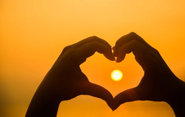 Hand making heart shape over sunset — Stock Photo, Image