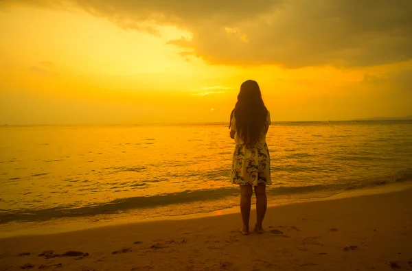 Mulher de pé na praia olhando para o pôr do sol — Fotografia de Stock