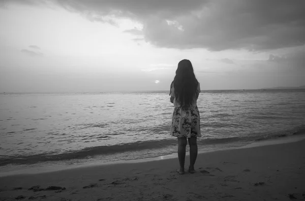 Femme debout sur la plage regardant le coucher du soleil — Photo