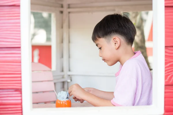 Liten pojke sitter i trädet hus äta glass — Stockfoto