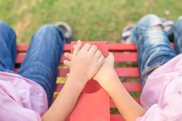 Kleine Geschwister sitzen und halten Hand in Hand im Park — Stockfoto