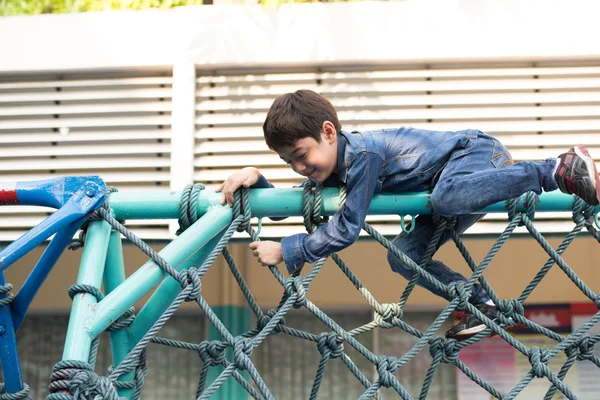 Niño subiendo a la cuerda en el patio de recreo — Foto de Stock