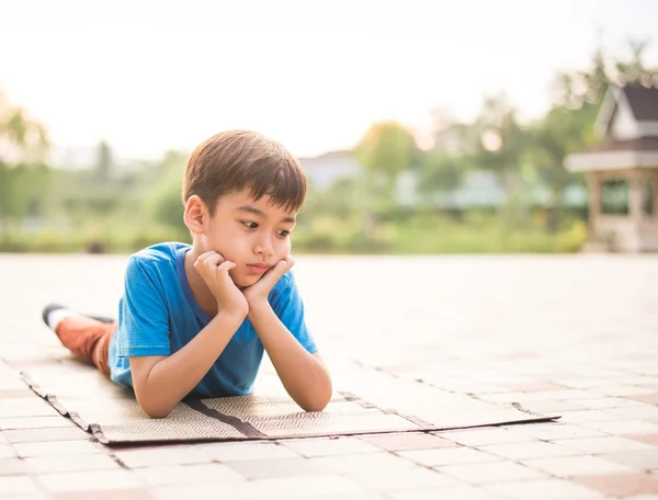 Маленький хлопчик сидить у парку сам — стокове фото