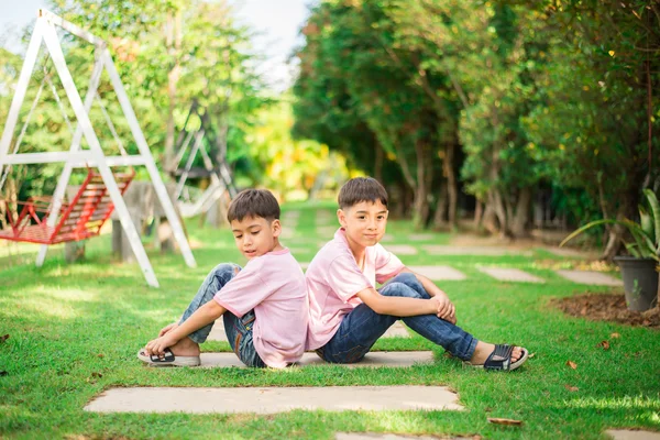 Lilla syskon pojke sitter tillsammans i parken — Stockfoto