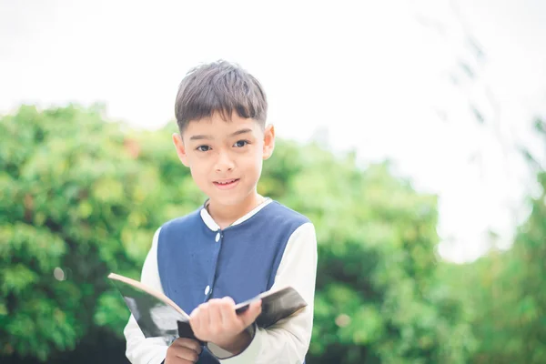 Petit garçon lisant un livre dans le parc — Photo