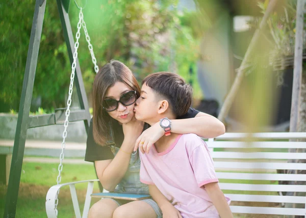 Маленький мальчик целует женщину в парке — стоковое фото