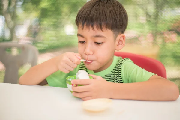 Маленький мальчик ест мороженое с кокосовым молоком — стоковое фото