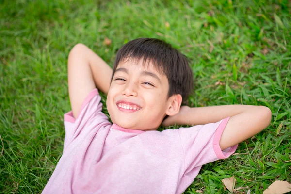 Jongetje vast op het gras met glimlach — Stockfoto