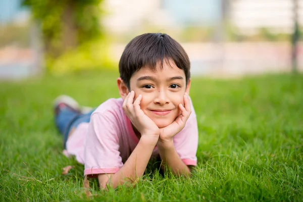 Pequeño niño acostado en la hierba con sonrisa — Foto de Stock