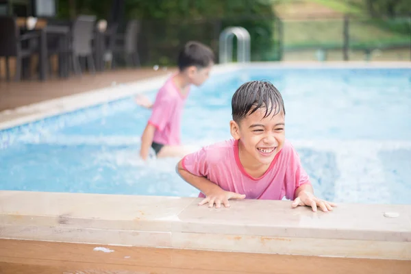 Pequeño hermano jugando en la piscina — Foto de Stock