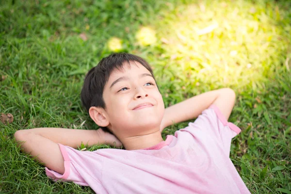 Маленький хлопчик лягає на траву, що мріє світло — стокове фото