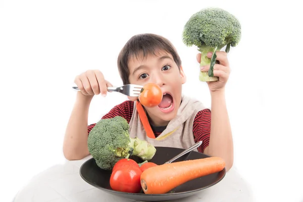 Kleine jongen eten plantaardige op schotel op witte achtergrond — Stockfoto