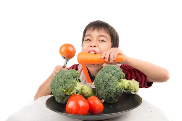 Мальчик ест овощи на белом фоне — стоковое фото