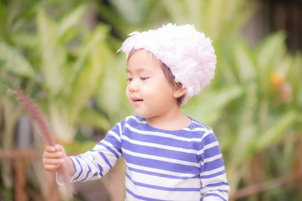 Petite fille asiatique mignonne touchant herbe de fleur — Photo