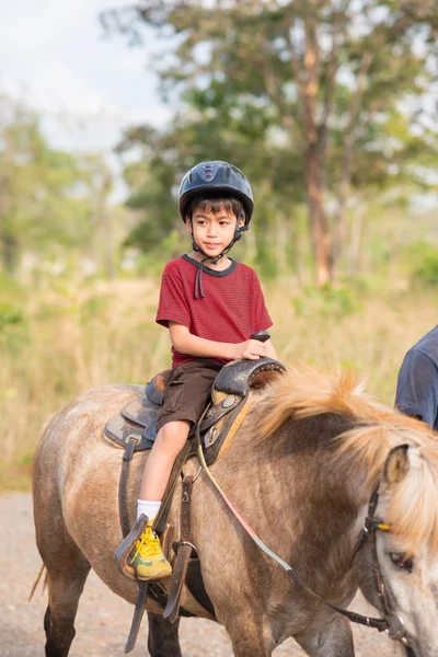Malý chlapec jezdecké výcviku koně — Stock fotografie