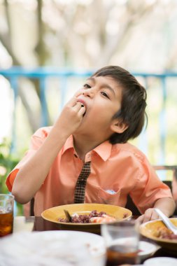 Küçük çocuk açık restoranda yemek yemek için yemek