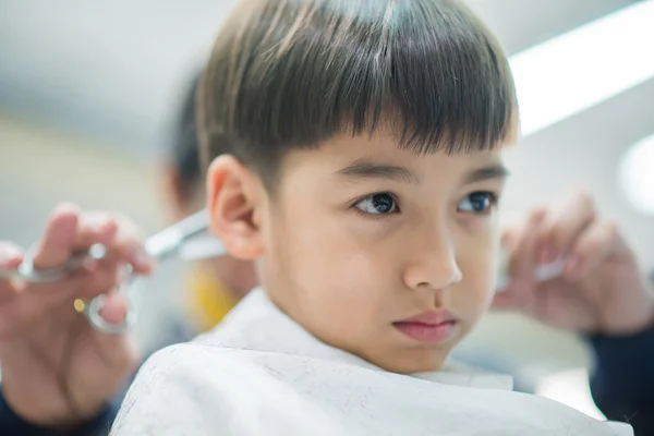 Menino sentado para cortar o cabelo na barbearia — Fotografia de Stock