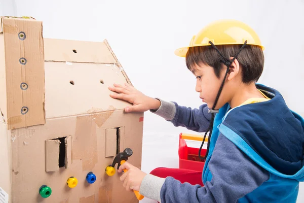 Kleine jongen doen alsof een monteur gebruiken hulpmiddelen te corrigeren en het papier huis — Stockfoto