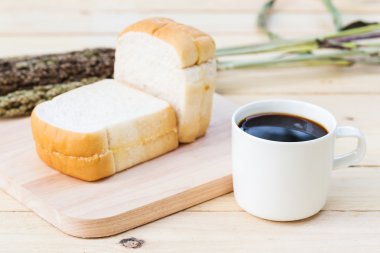 Kahve fincanı ve ahşap zemin üzerinde ekmek 