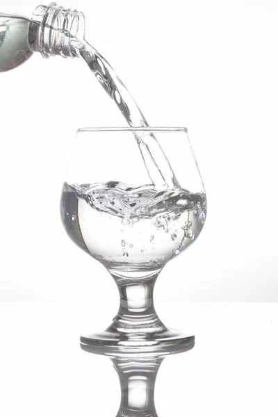 Acqua versando in bicchiere di vino su sfondo bianco — Foto Stock