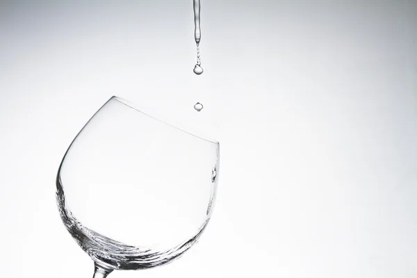 Gota de agua en copa de vino sobre fondo blanco — Foto de Stock