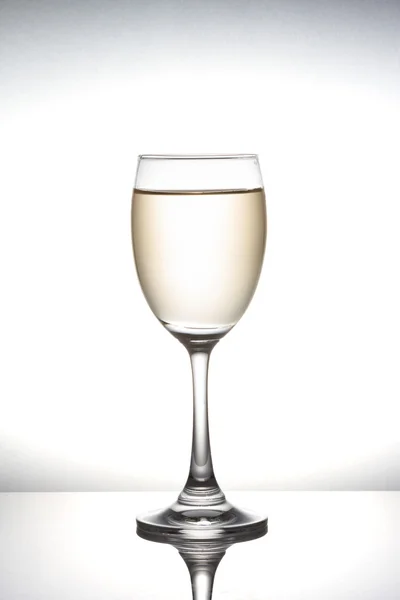 White wine pouring into wineglass on white background — Stock Photo, Image