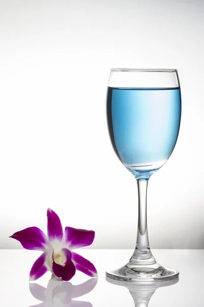 在酒杯和兰花在白色背景上的蓝色鸡尾酒 — 图库照片