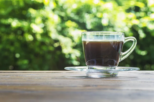 Kaffeetasse auf dem Tisch und grünes Bokeh — Stockfoto