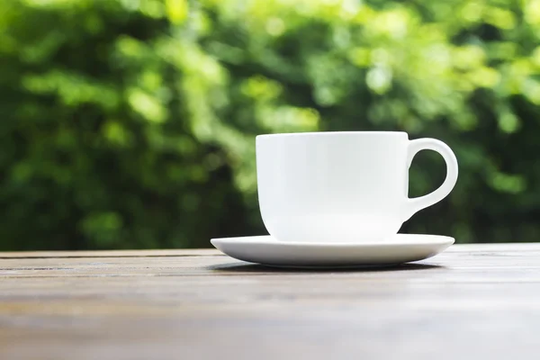 背景のボケ味の緑に白いコーヒー カップ — ストック写真