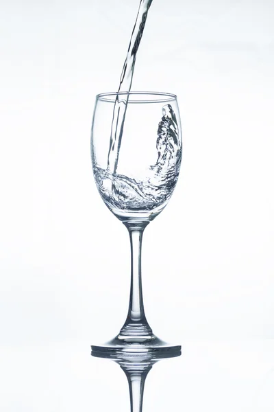 Water pouring into a vine glass on white — Stock Photo, Image