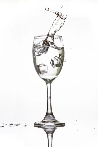 Hielo cayendo en un vaso de agua haciendo agua de forma extraña — Foto de Stock