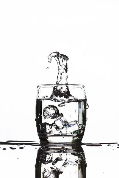 Ice dropping into a glass of water making strange shape water — Stock Photo, Image