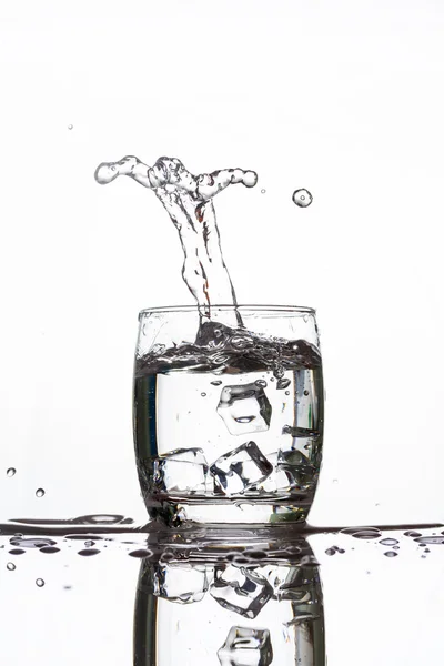 Ice dropping into a glass of water making strange shape water — Stock Photo, Image