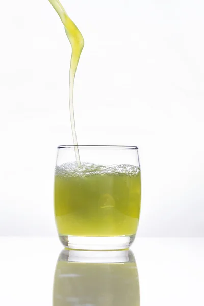 Zumo de fruta verde vertiendo en un vaso sobre fondo blanco — Foto de Stock